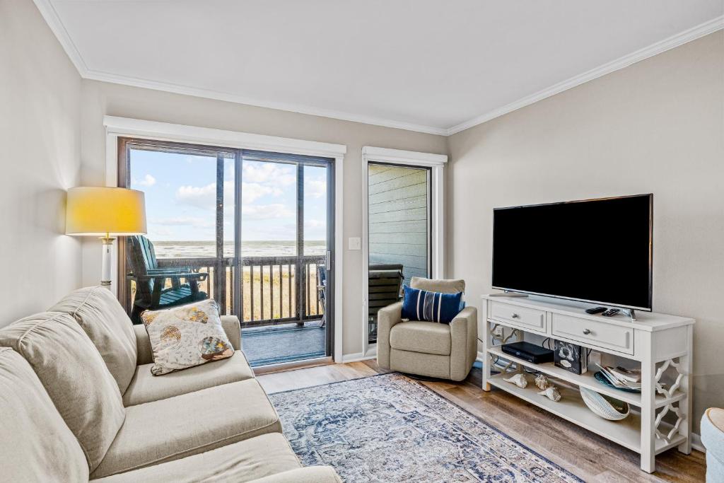 ein Wohnzimmer mit einem Flachbild-TV und einem Sofa in der Unterkunft Dunescape Villas 255 in Atlantic Beach