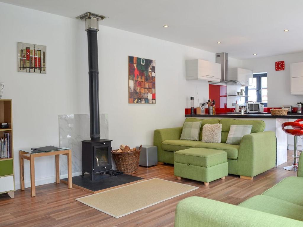 a living room with a green couch and a stove at Townsend Pod in Greinton