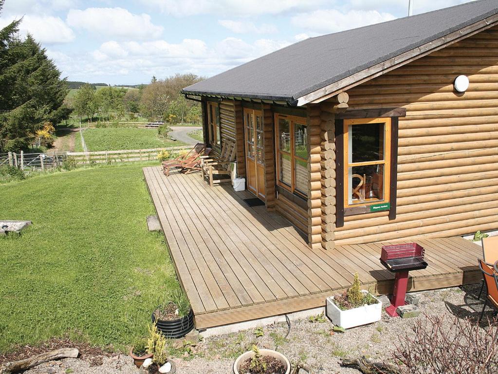 a cabin with a wooden deck in a yard at Bracken Log Cabin - S4468 in Glenfarg