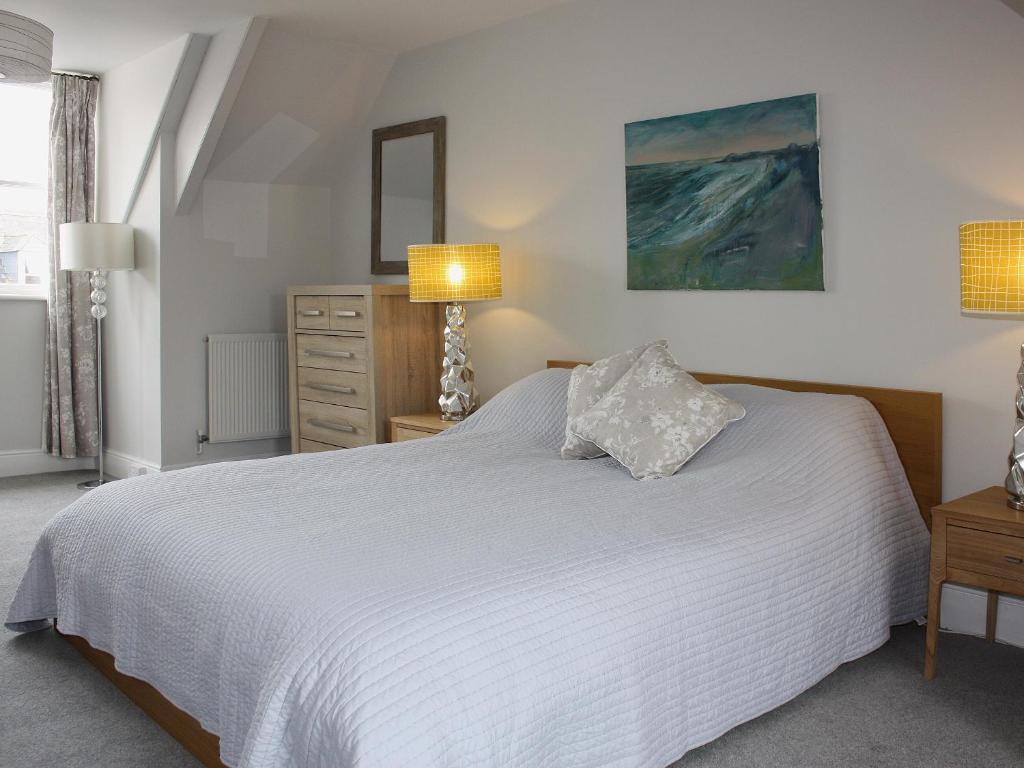 a bedroom with a white bed and a dresser and a mirror at Burford in Penzance