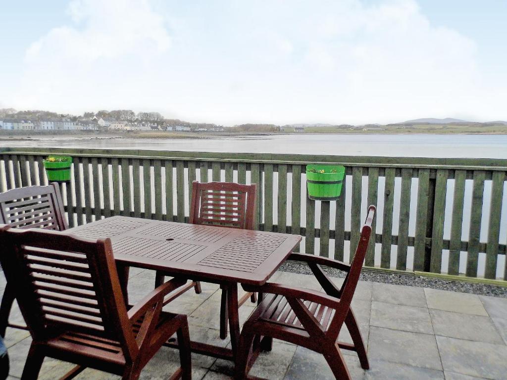 a wooden table and chairs on a balcony with the water at Seaview in Garlieston