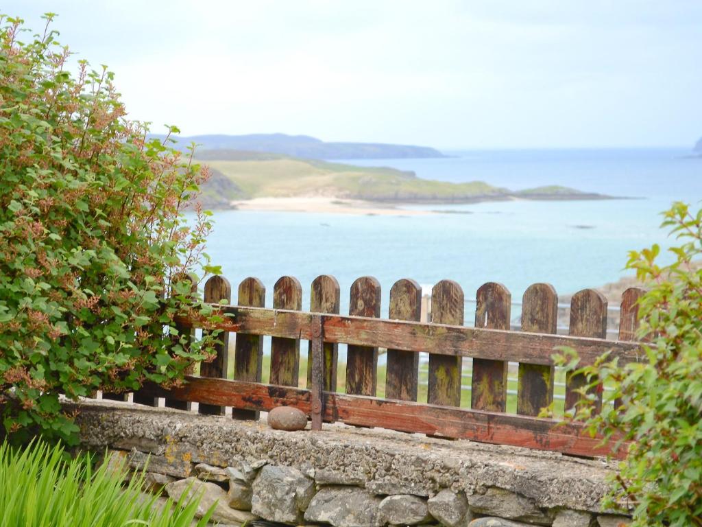 a wooden bench with a view of the ocean at Bydand Cottage in Melness