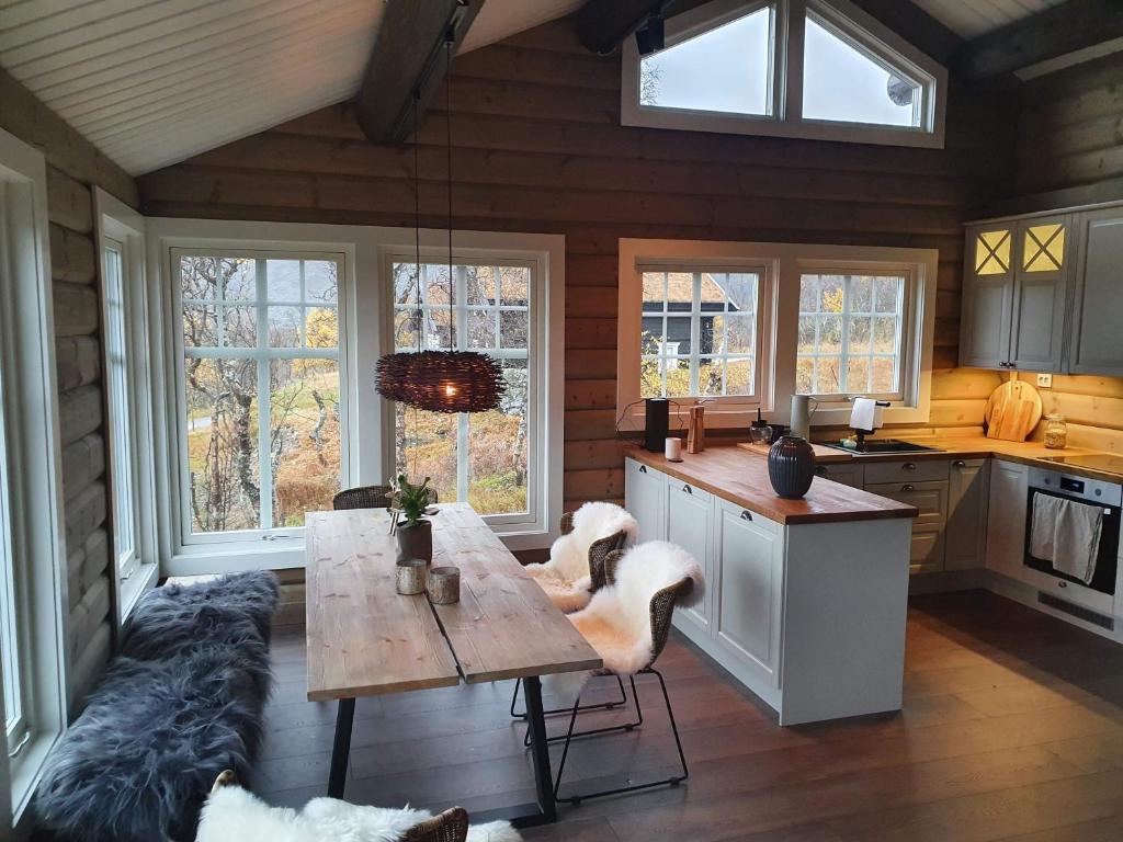 a kitchen with a table and chairs and windows at New, Mountain paradise, fishing, biking, mountaineering in Tyinkrysset