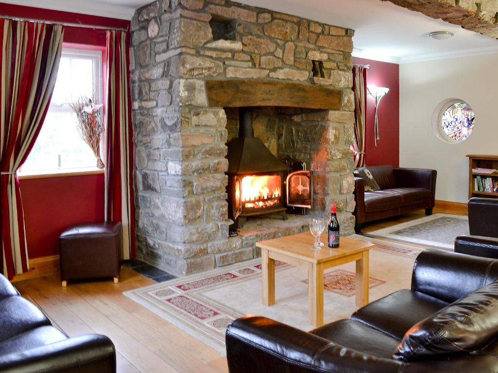 a living room with a stone fireplace and leather furniture at Ty-canol in Ferryside