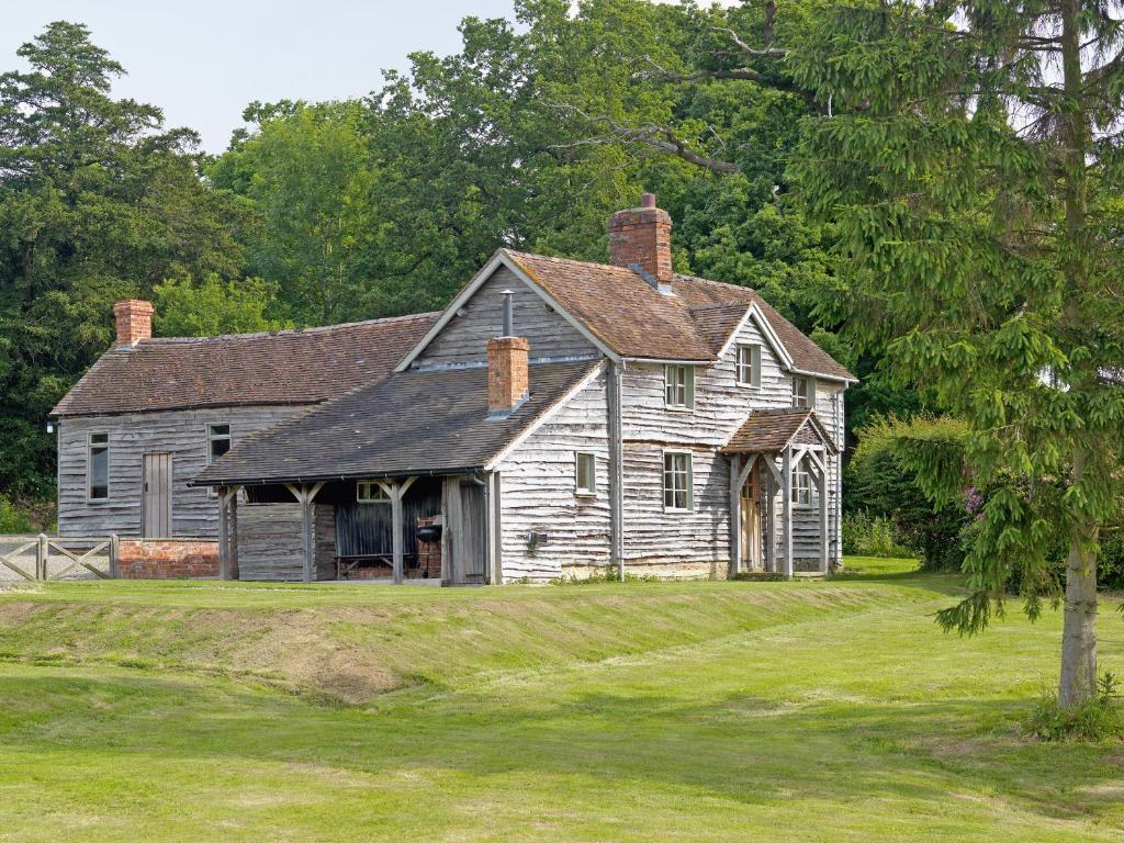 una casa vieja sentada en un campo de hierba en The Shooting Lodge, en Acton Scott