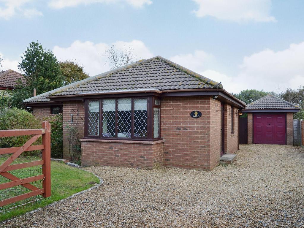 a small brick house with a red garage at Gearys in Freshwater