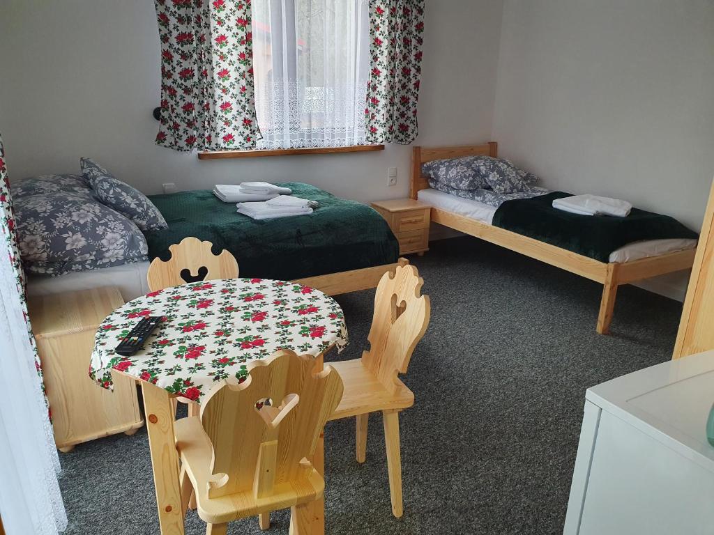 a room with two beds and a table and chairs at Przy Tartaku in Jurgów