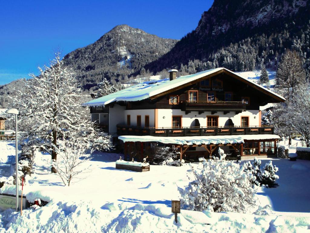 a house in the snow with mountains in the background at Madlgut in Lofer