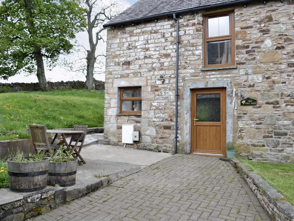 um edifício de pedra com uma porta de madeira e uma mesa de piquenique em The Calf Shed em Alston