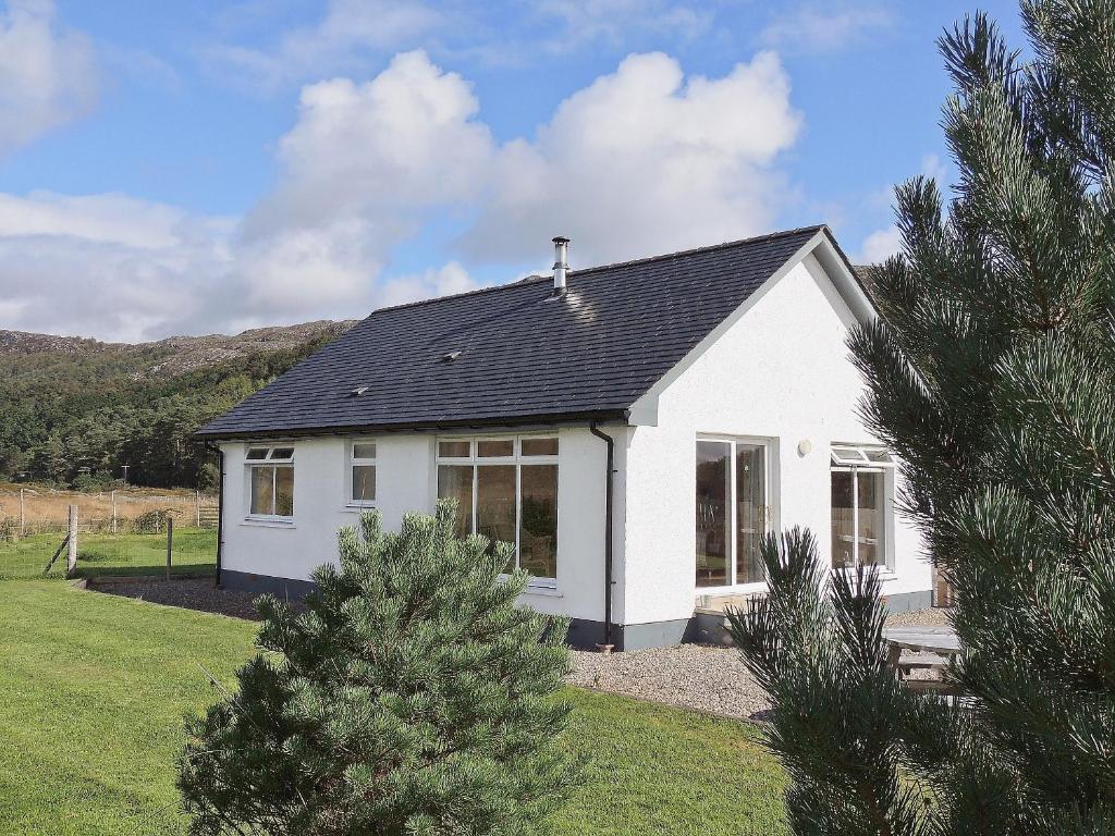 a white house with a black roof at Riverview Cottage in Acharacle