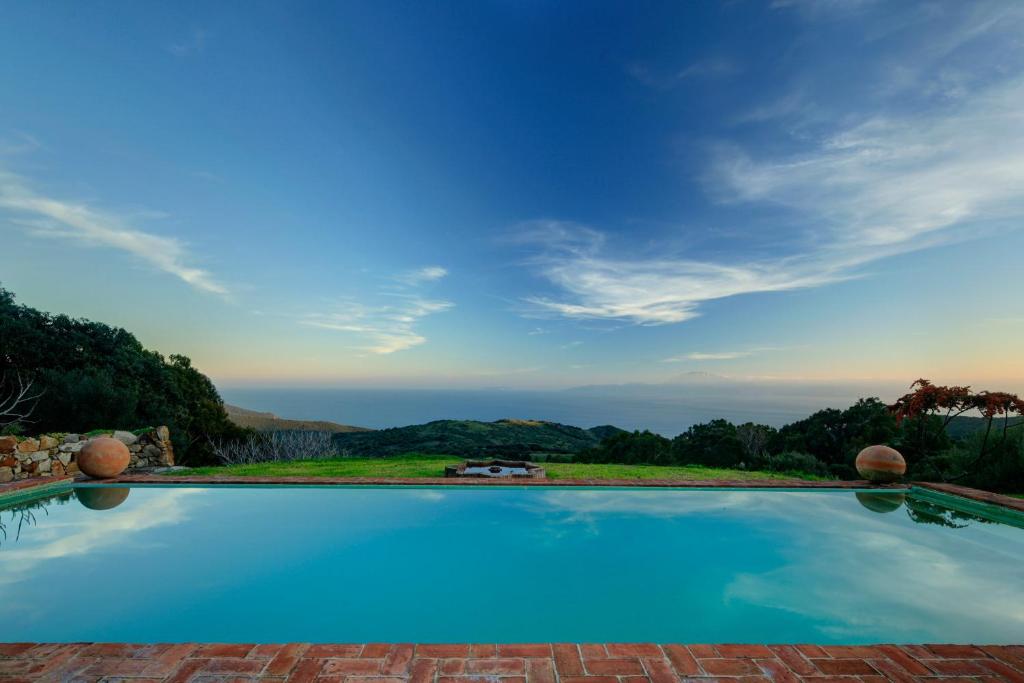 a large swimming pool with a view of the ocean at Cortijo La Hoya in El Bujeo