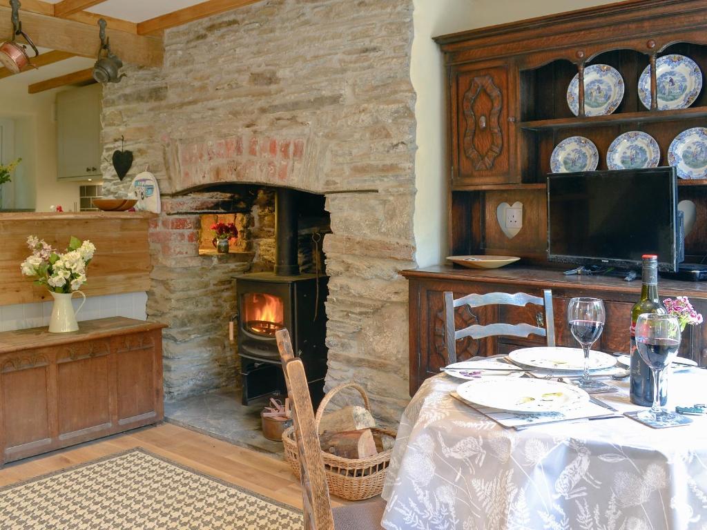 a dining room with a table and a stone fireplace at Annies Cottage in Buckland Monachorum