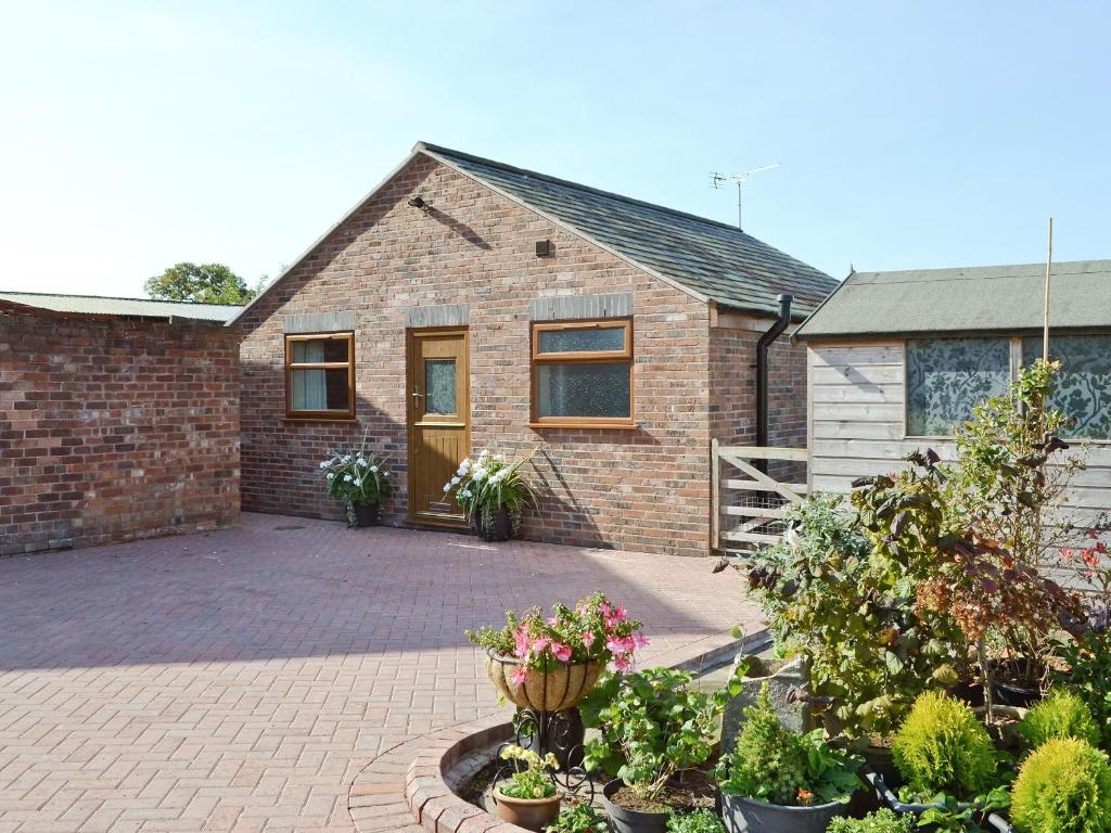 a brick house with plants in front of it at Weetwood Lodge in Kelsall