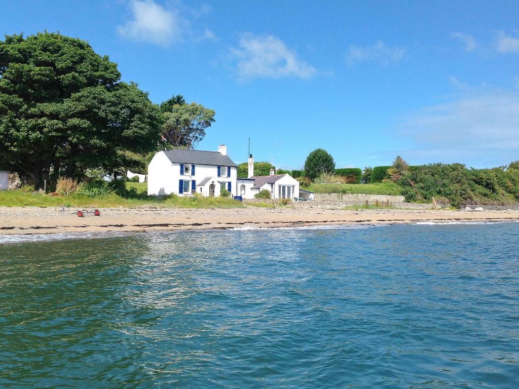 a white house on the shore of a beach at Blue Sails-jpv in Llangoed