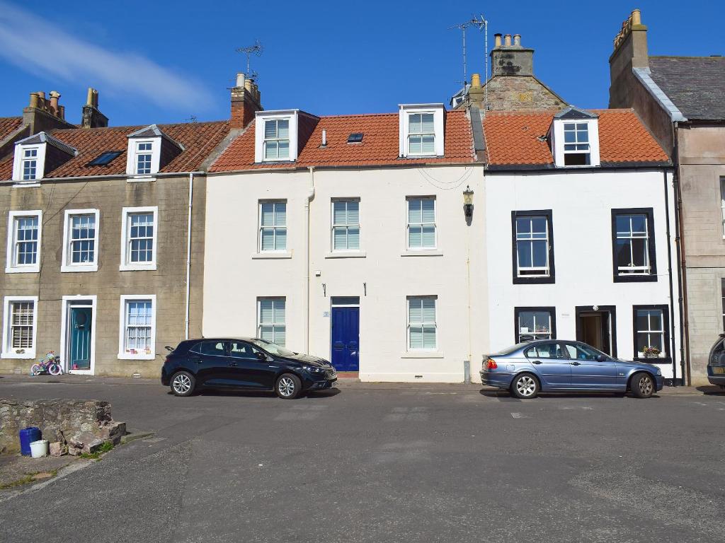 two cars parked in front of a white building at Nautilus Cottage in Cellardyke
