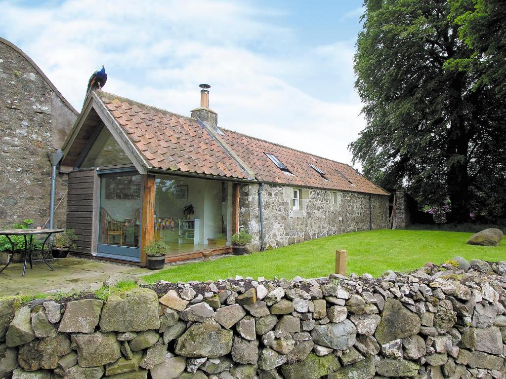 an old stone house with a stone wall at Tullibole Castle Longhouse in Crook of Devon