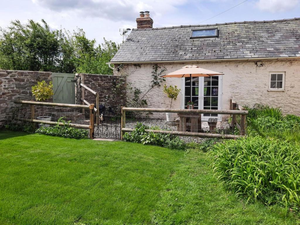 a cottage with an umbrella in a yard at The Cider Barn in Presteigne