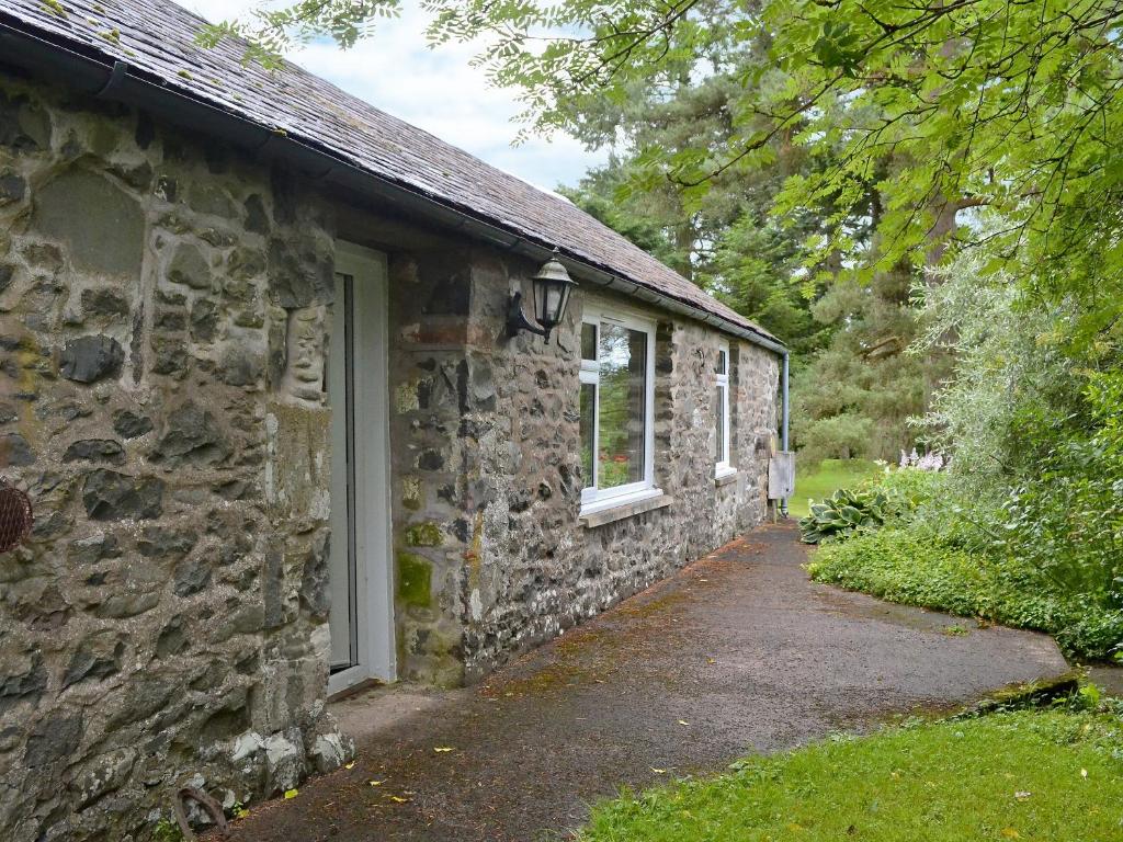 a stone building with a door and a window at Dye Mill Cottage in Moffat