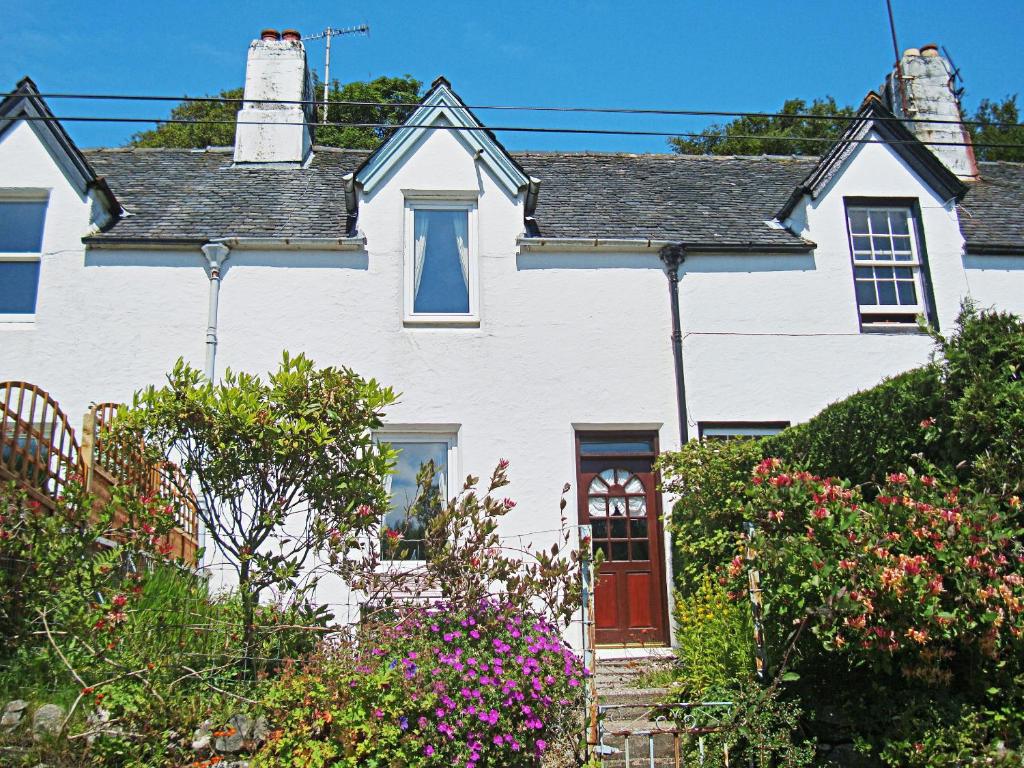 una casa blanca con una puerta roja y algunas flores en 15 Cairnbaan Cottage, en Cairnbaan
