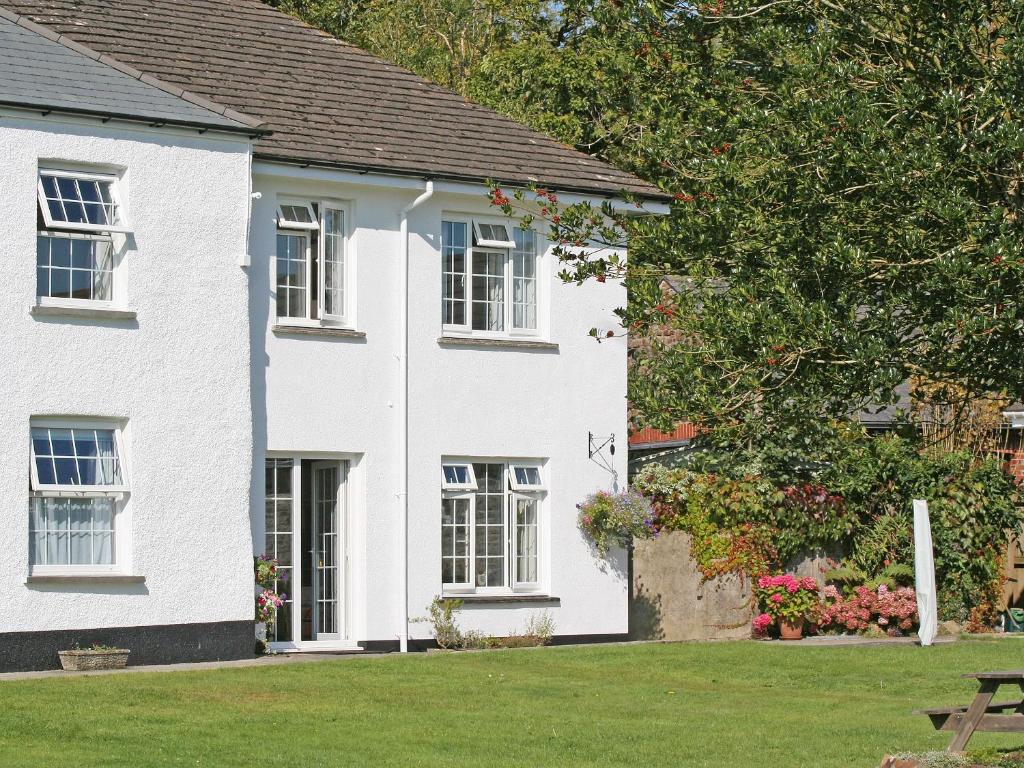 a white house with white windows and a yard at Jubilee Cottage in Pyworthy