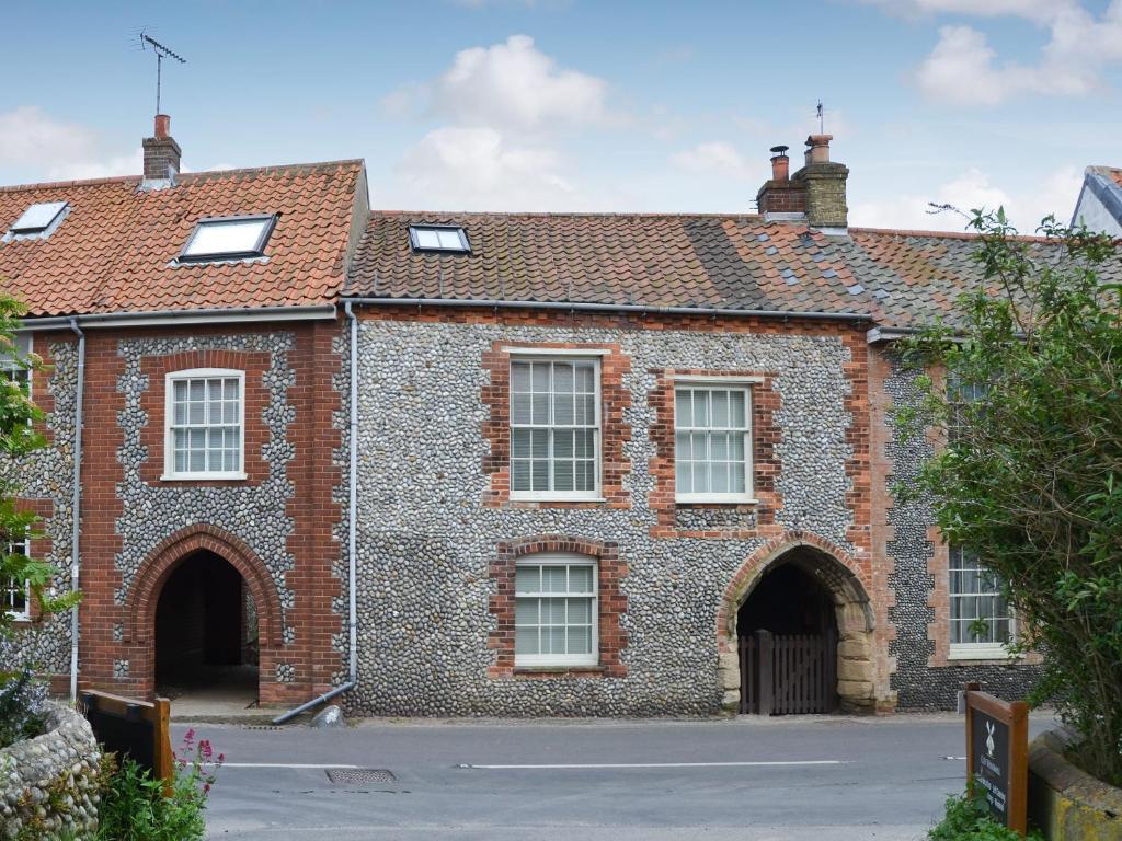 an old brick building with a gate and a roof at Maison De Quai in Cley next the Sea