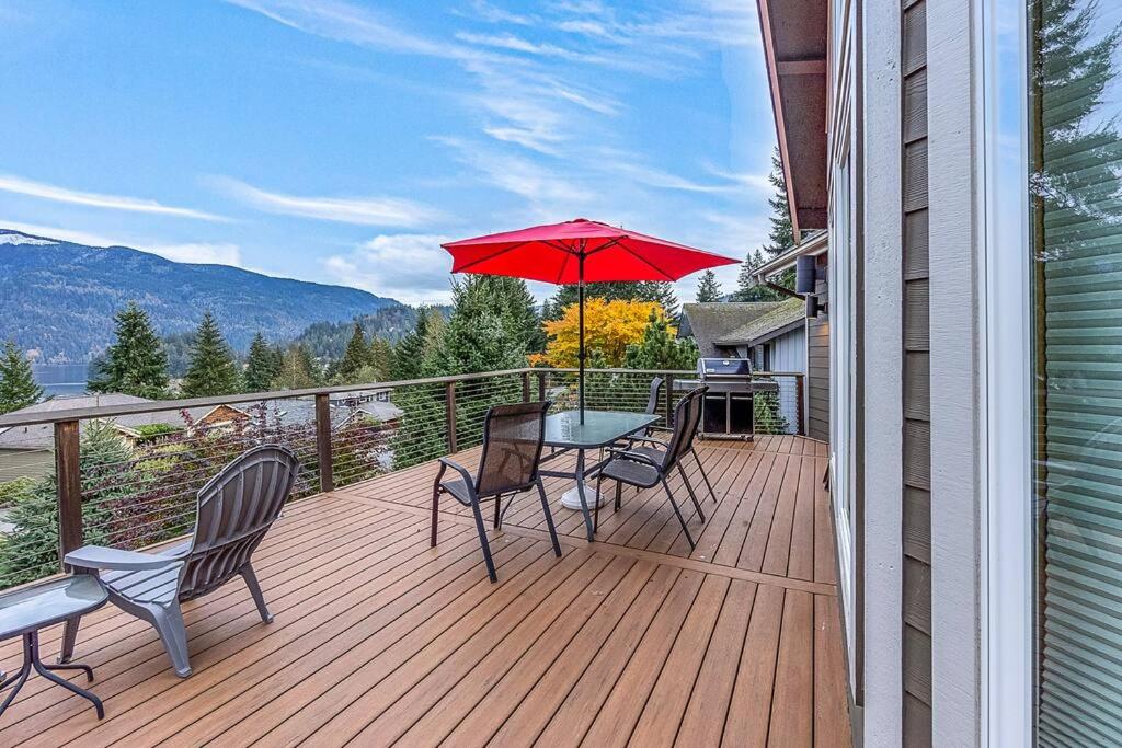 een terras met een tafel en stoelen en een rode parasol bij Mountain Lake View Lodge in Bellingham