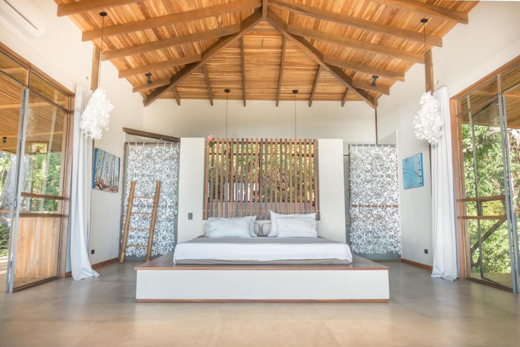 ein Schlafzimmer mit einem Bett in einem Zimmer mit Fenstern in der Unterkunft SELVA RESORT Ocean View Luxury Villas in Playa Santa Teresa