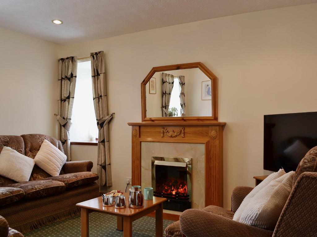 a living room with a fireplace and a mirror at Ross Cottage in Cairneyhill