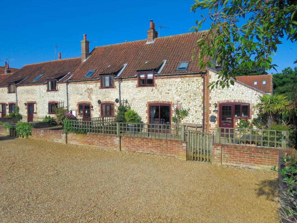 an old house with a fence in front of it at Mallards in Thornham