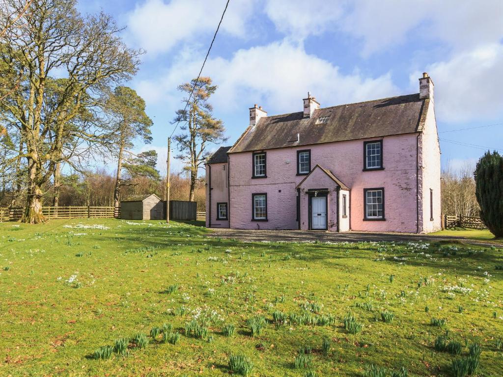 an old pink house in a field of grass at Lochenkit Farmhouse in Corsock