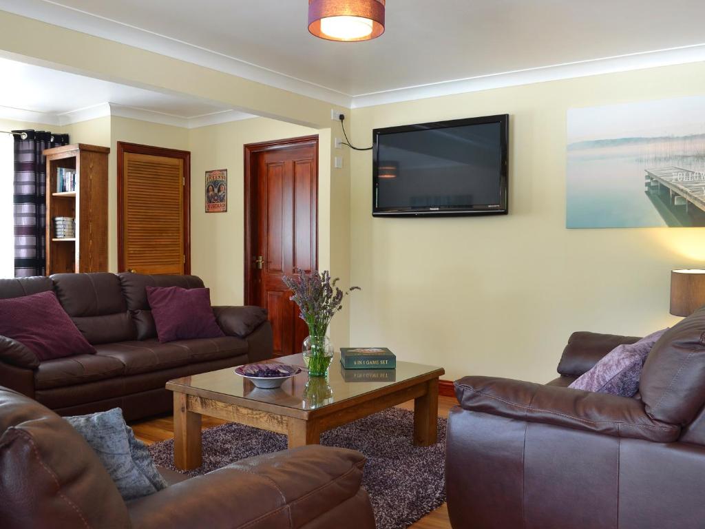 a living room with couches and a tv on the wall at The Lodge in Brandesburton