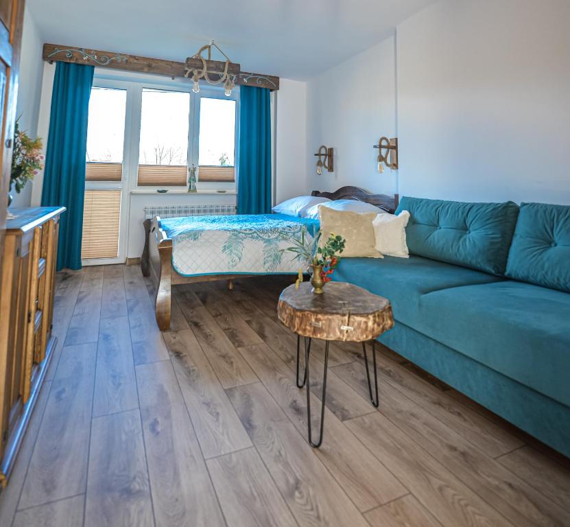 a living room with a blue couch and a table at Apartament Zielony Ruczaj w Cisnej in Cisna