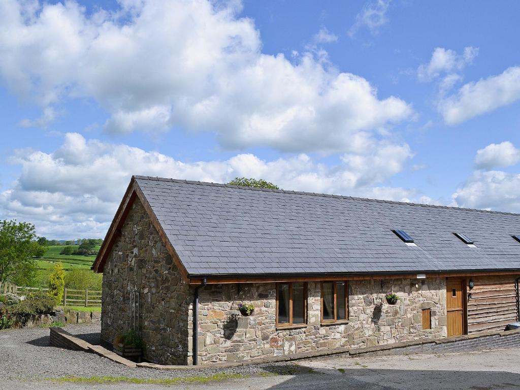 een stenen huis met een dak op een weg bij Y Dderwen At Brynglas Farm in Llanfair Caereinion
