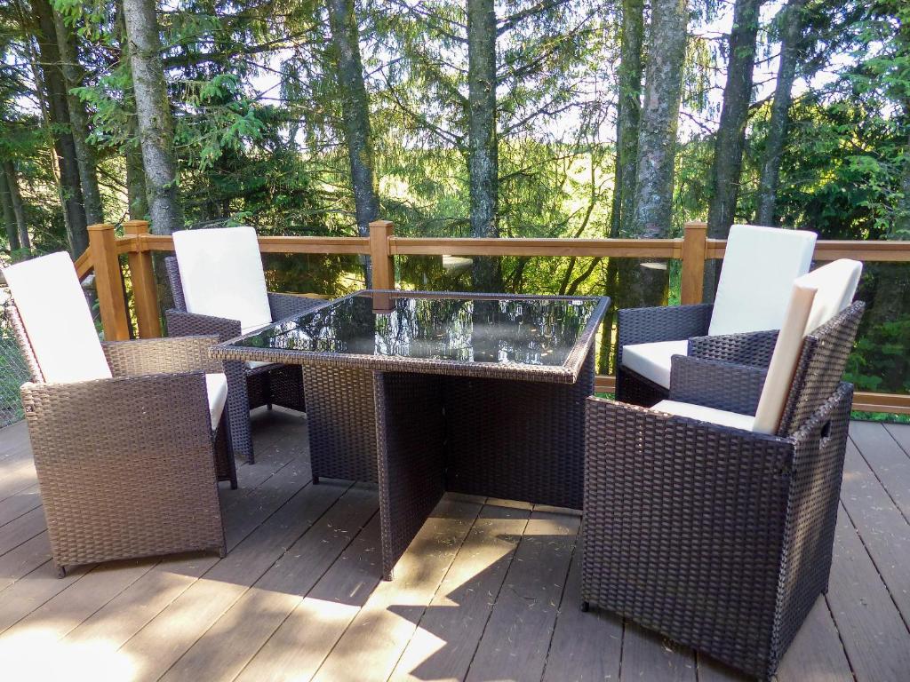 a patio with a glass table and chairs on a deck at Ash Lodge in Clatworthy