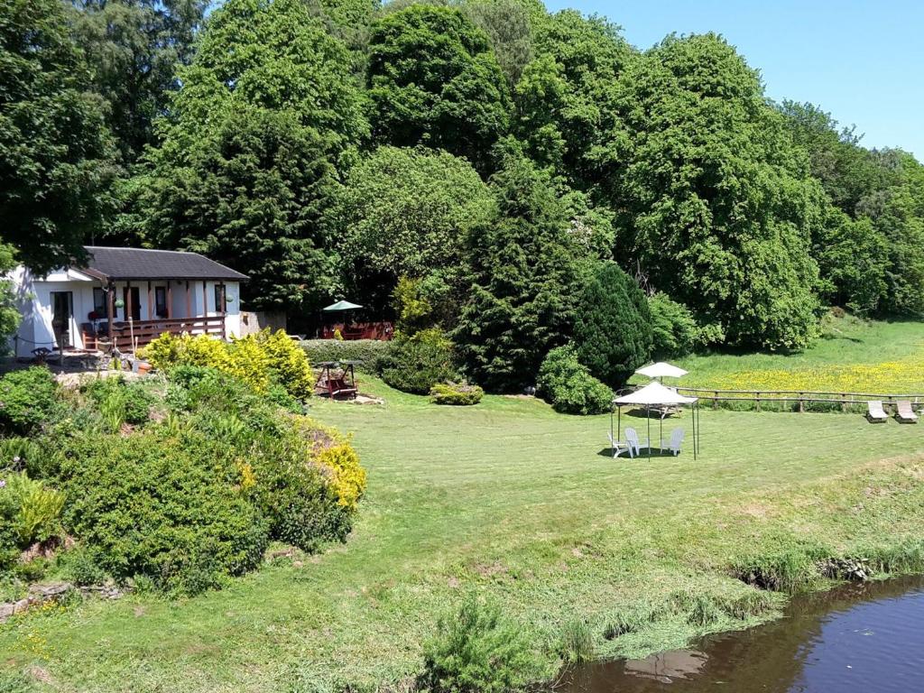 a garden with a tent and a house next to a river at Harperfield Chalet in Lanark