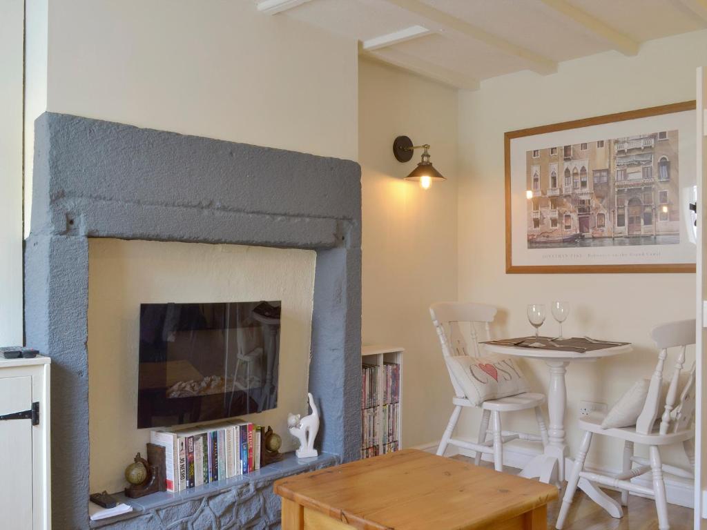 a living room with a fireplace and a table at Cosy Nook in Cromford