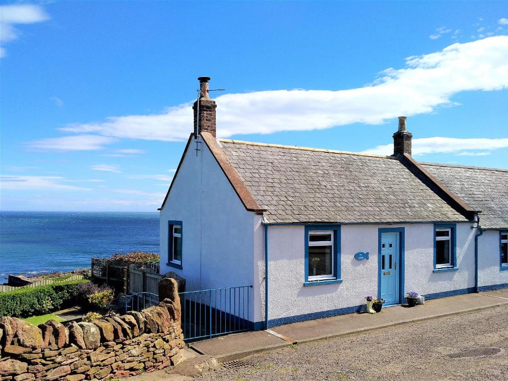 a white house with a blue door and the ocean at The Lucken in Auchmithie