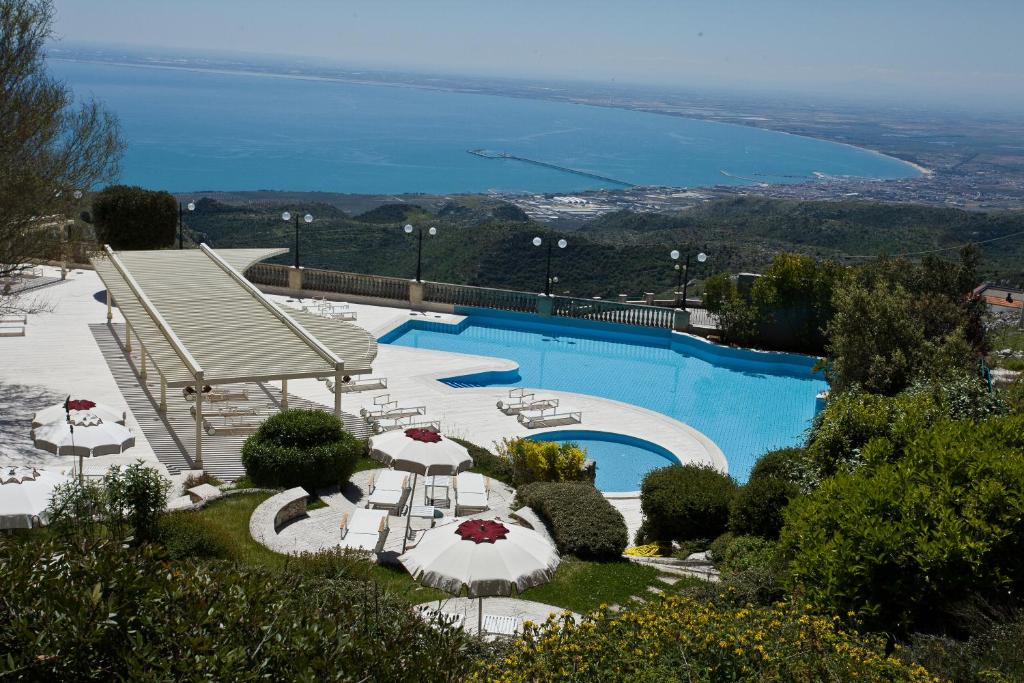 einen Pool mit Stühlen und Sonnenschirmen sowie das Meer in der Unterkunft Palace Hotel San Michele in Monte SantʼAngelo