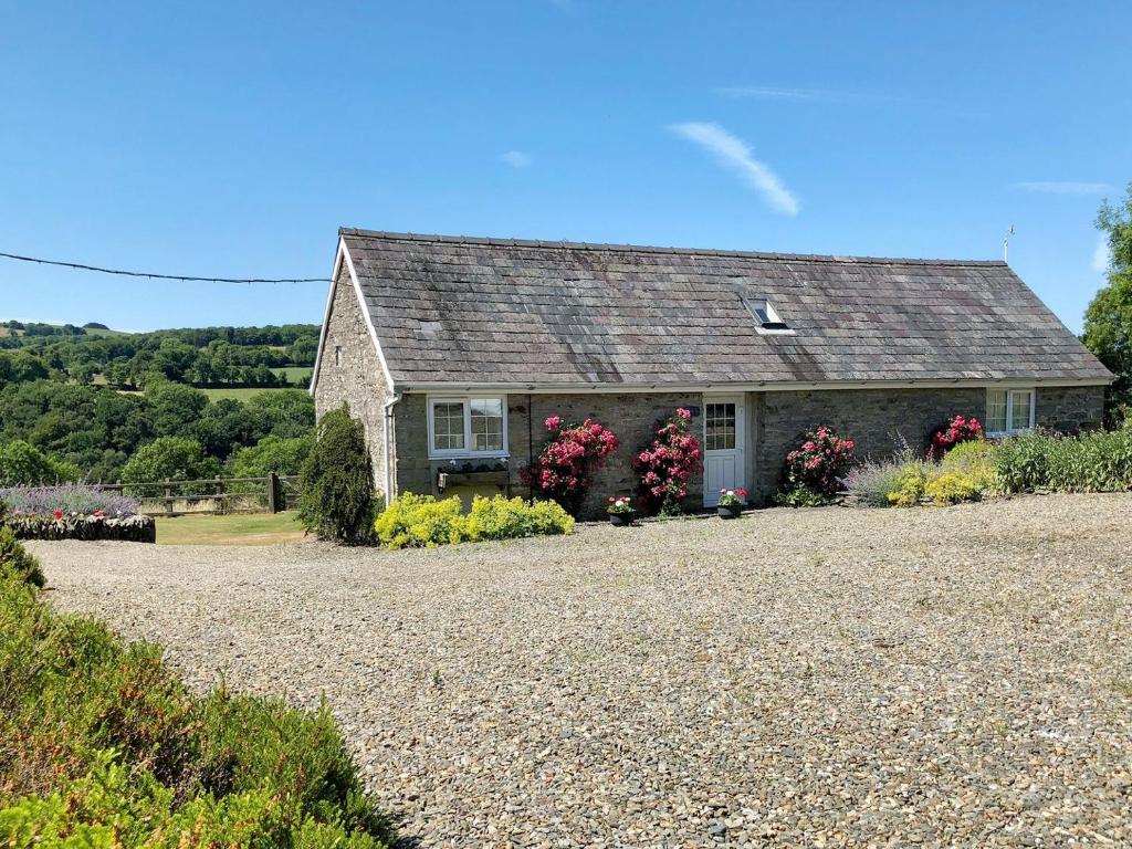 a stone house with flowers in front of it at Cych Cottage in Capel-Ifan