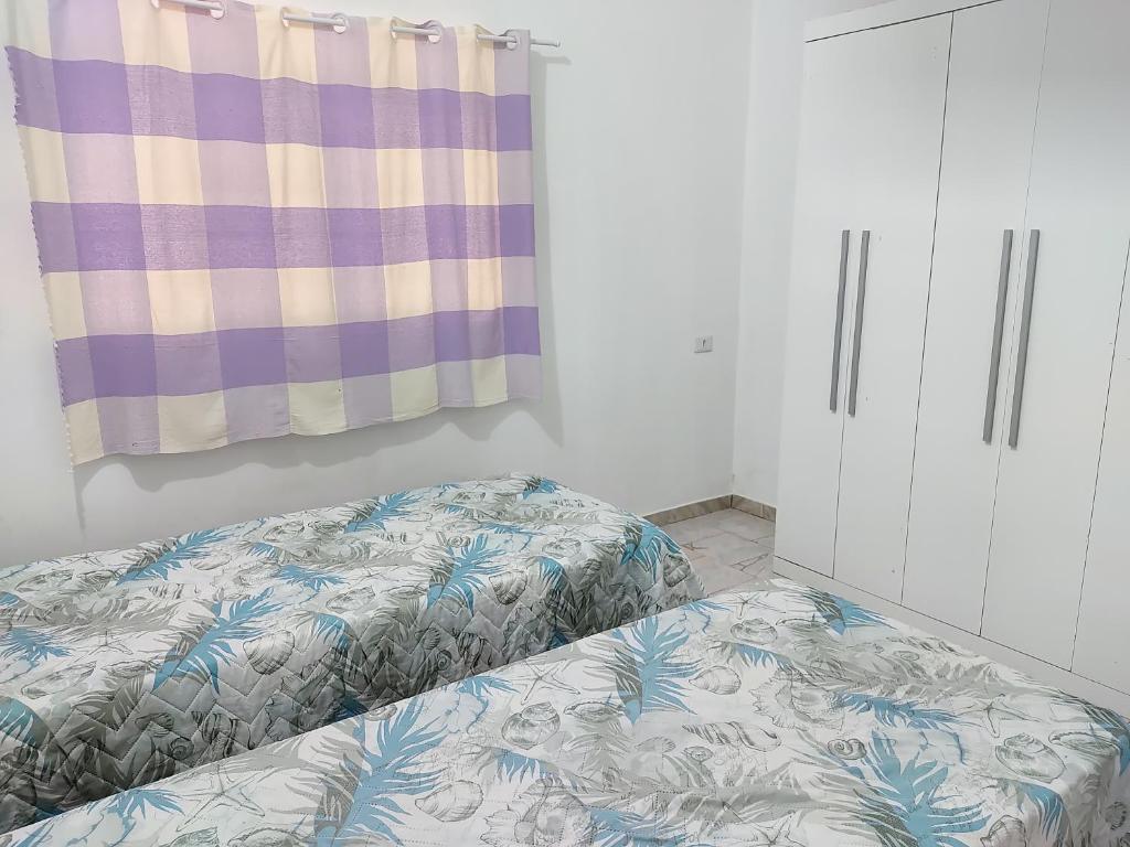 a bedroom with two beds and a curtain at Casa Agradável próxima ao Bosque in Pôrto Feliz