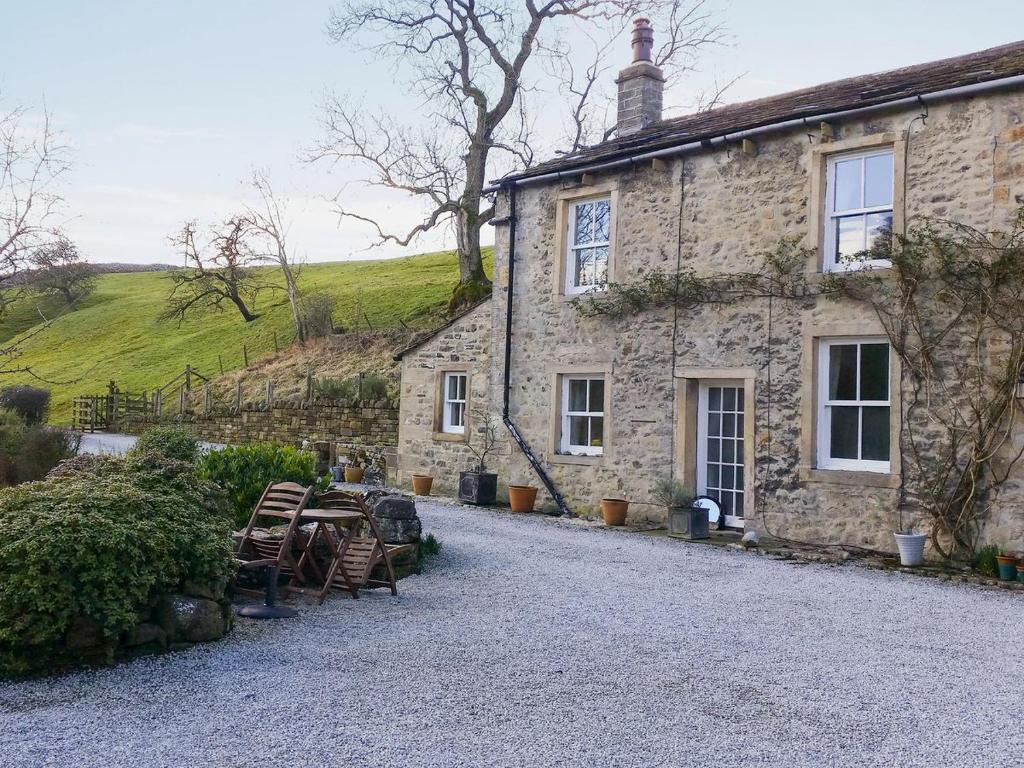 a stone house with chairs and tables in front of it at Miller Cottage in Malham