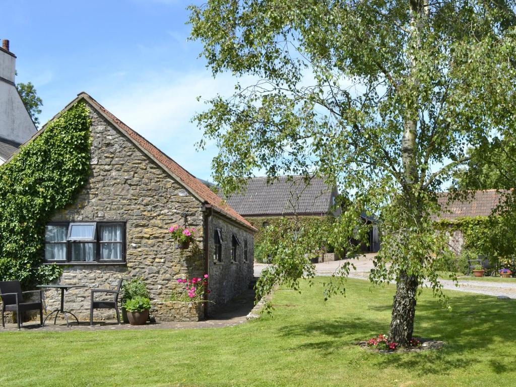 une maison en pierre avec un arbre dans la cour dans l'établissement Ramscliff Cottage, à Cheddar