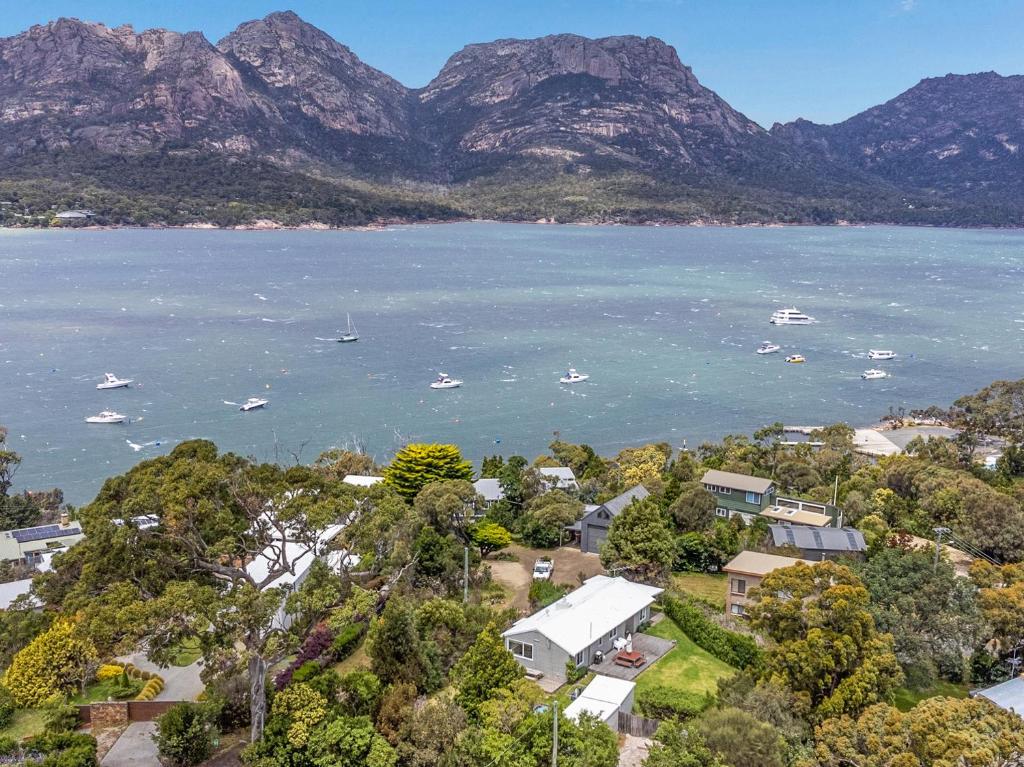an aerial view of a town and the water with mountains at Fish @ Freycinet in Coles Bay