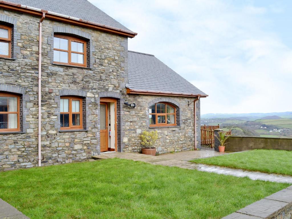 a stone house with a green lawn in front of it at 5 Pengraig Draw in Llanychaiarn