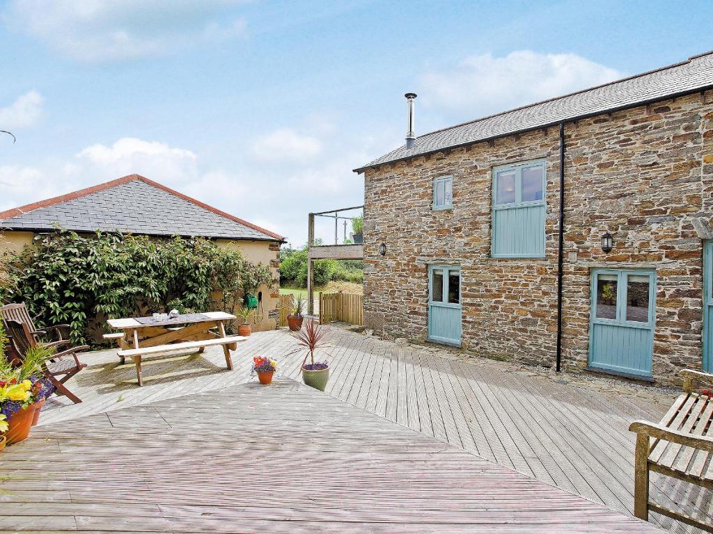 a brick house with a wooden deck and a bench at Lower Trevorder Barn-tt2 in Warleggan