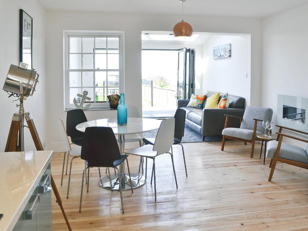 een woonkamer met een tafel en stoelen en een bank bij Coastguard Cottage in Chestfield