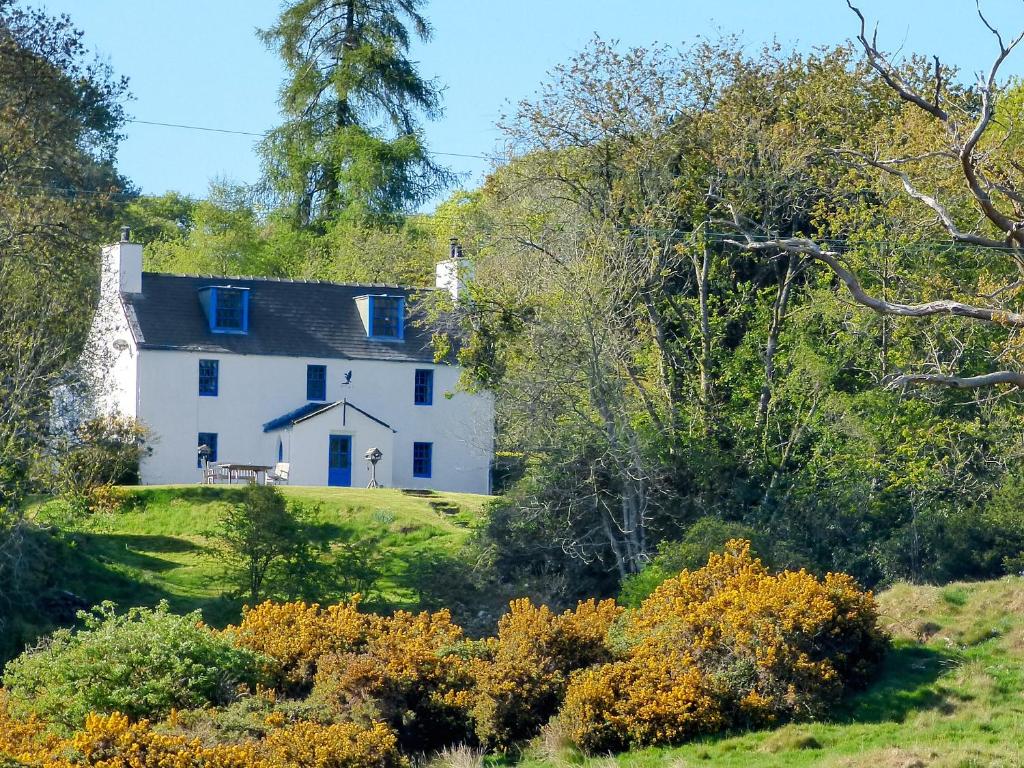 une maison blanche sur une colline avec des arbres dans l'établissement Little Boreland, à Gatehouse of Fleet