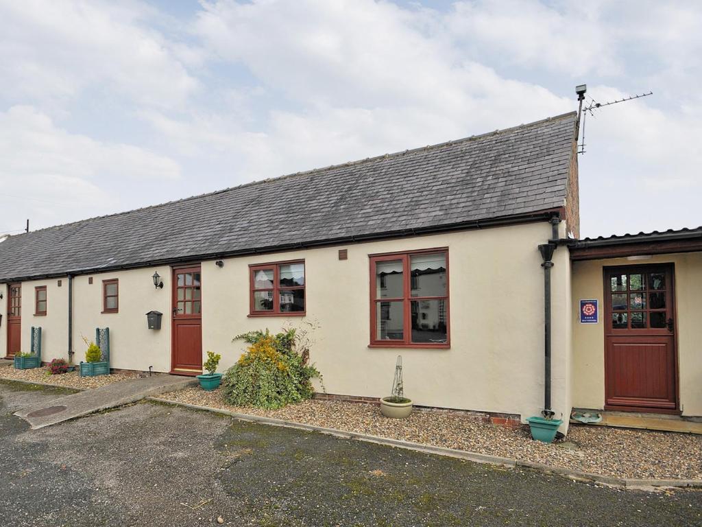 a white building with red doors and windows at Swallow Cottage in Ferryhill