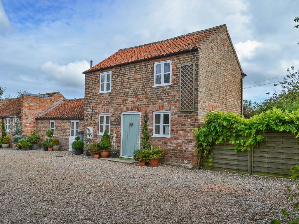 a brick house with a blue door at Wisteria Cottage - E5094 in Chapel Saint Leonards