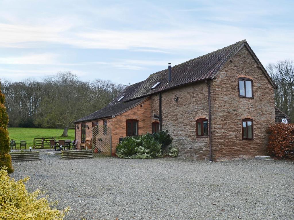 an old brick building with a table in a field at Howards End in Leysters